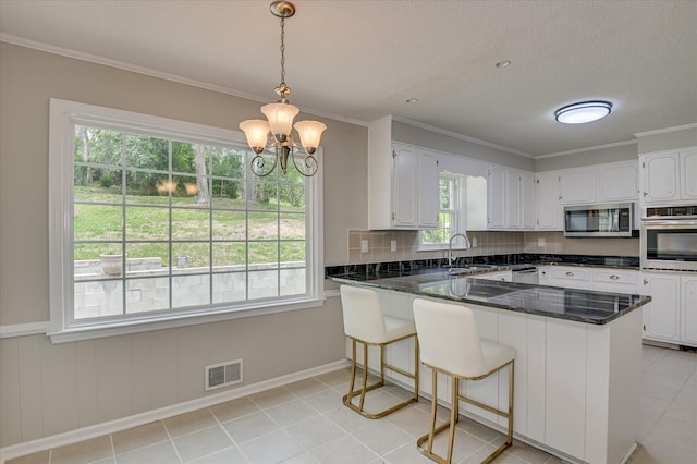 986 Campbellton Dr, North Augusta, SC 29841 - kitchen featuring stainless steel appliances, a peninsula, white cabinetry, a chandelier, and ornamental molding