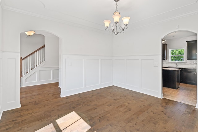207 Hazelwood Ct, Grovetown, GA 30813 - unfurnished dining area with a decorative wall, ornamental molding, a chandelier, dark wood-style floors, and arched walkways