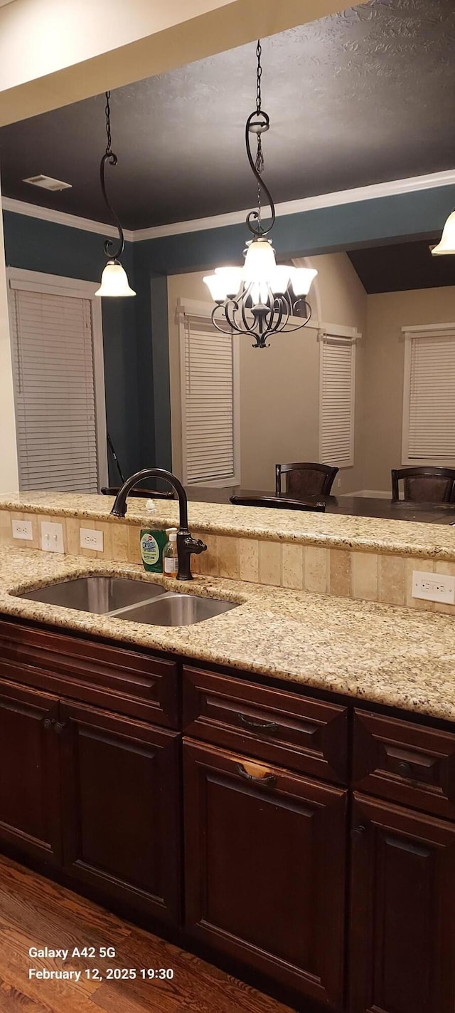 kitchen with dark brown cabinets, a sink, and decorative light fixtures