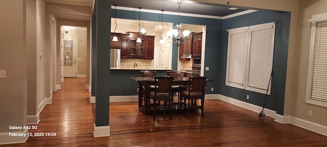 dining room featuring baseboards, ornamental molding, dark wood finished floors, and an inviting chandelier