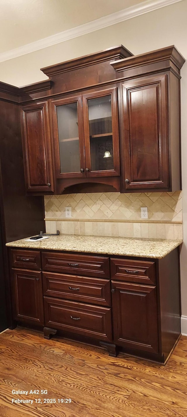 bar featuring ornamental molding, backsplash, and wood finished floors