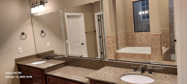 bathroom featuring double vanity, a garden tub, and a sink