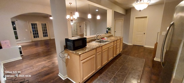 kitchen with arched walkways, pendant lighting, light brown cabinets, a sink, and black microwave