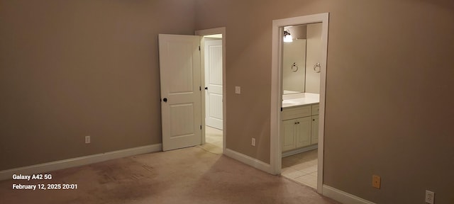 unfurnished bedroom with light colored carpet, ensuite bath, and baseboards