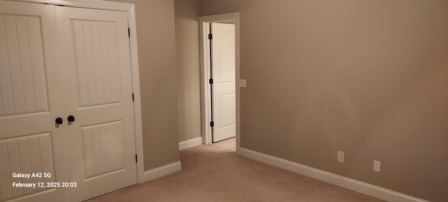 unfurnished bedroom with baseboards, a closet, and light colored carpet