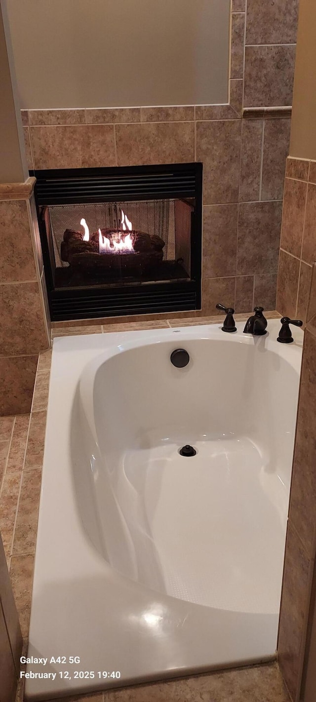 details with a bathtub and a multi sided fireplace