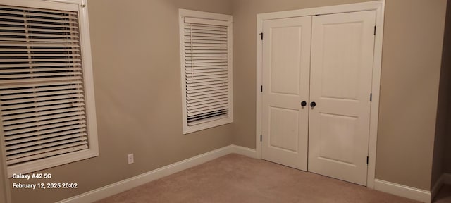 unfurnished bedroom featuring a closet, light carpet, and baseboards