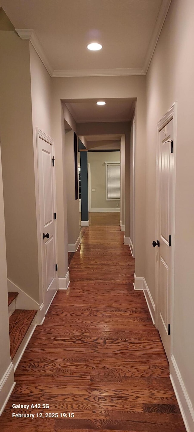 hall featuring ornamental molding, dark wood-style flooring, and baseboards