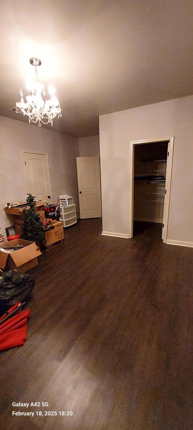 interior space featuring a chandelier, dark wood finished floors, and baseboards