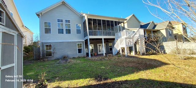 rear view of property with an outdoor fire pit, a lawn, fence, and a sunroom