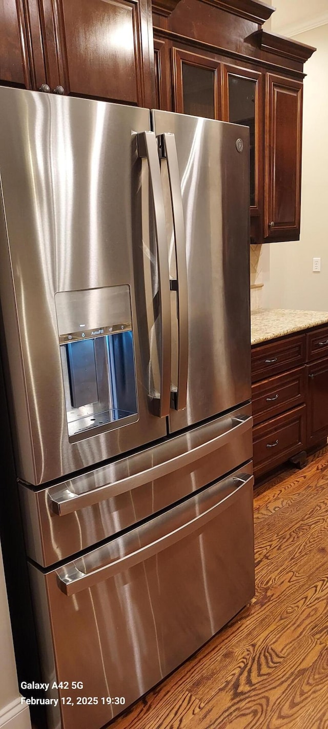 kitchen featuring light stone counters, light wood-type flooring, stainless steel refrigerator with ice dispenser, and dark brown cabinets