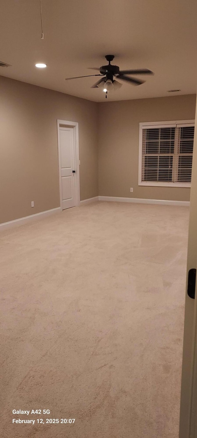 unfurnished room with baseboards, a ceiling fan, visible vents, and light colored carpet