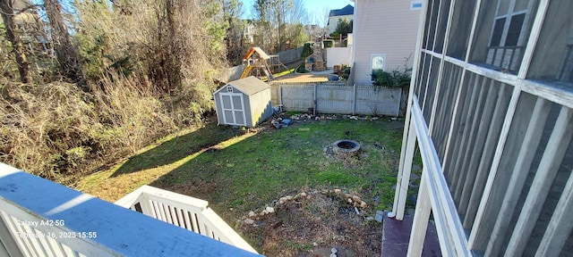 view of yard featuring a fire pit, a shed, an outdoor structure, and a fenced backyard