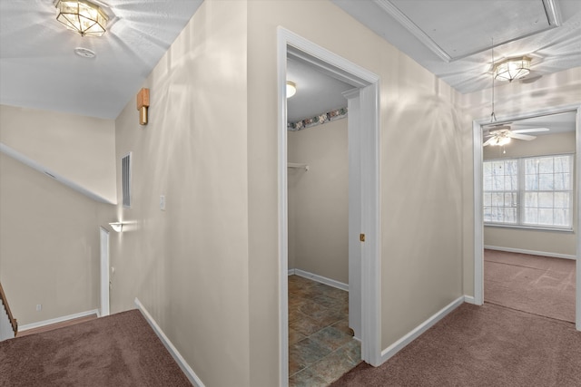 hallway with visible vents, attic access, carpet, and baseboards