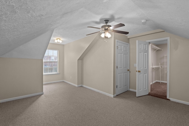 bonus room with lofted ceiling, baseboards, carpet floors, and a textured ceiling