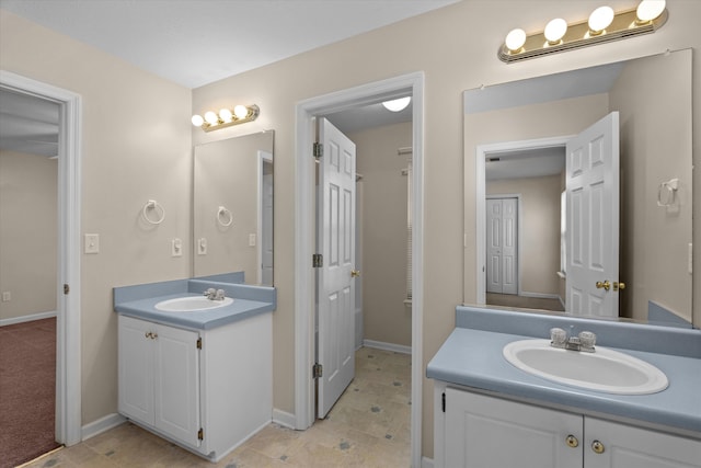 bathroom featuring a sink, baseboards, and two vanities