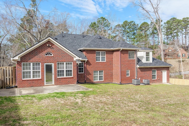 rear view of property featuring a patio, brick siding, central AC, and a lawn