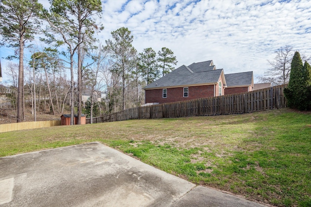 view of yard with a storage unit, a patio, an outbuilding, and a fenced backyard