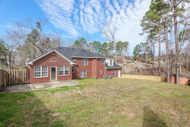 rear view of house with brick siding, a shingled roof, fence private yard, a yard, and a patio