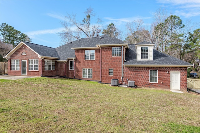 back of property with brick siding, central AC unit, a yard, and fence