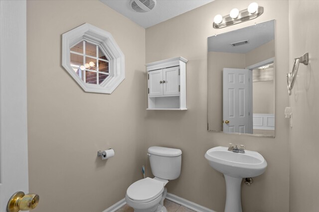 half bathroom featuring tile patterned floors, toilet, baseboards, and visible vents