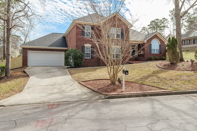 traditional-style house with brick siding, fence, roof with shingles, a garage, and driveway