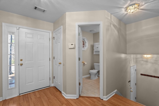 foyer entrance featuring light wood-style floors, visible vents, and baseboards