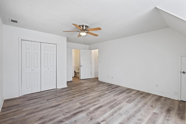 unfurnished bedroom with light wood-style floors, a closet, visible vents, and a textured ceiling