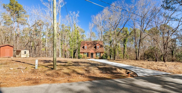 view of front of home featuring concrete driveway, a shed, and an outdoor structure