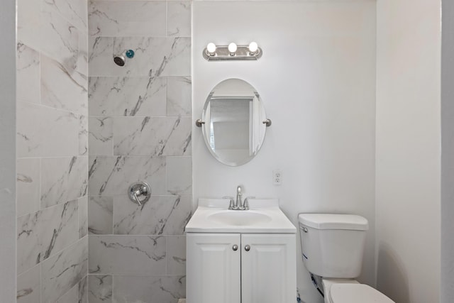 bathroom with toilet, a tile shower, and vanity