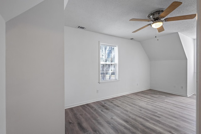 bonus room with lofted ceiling, a textured ceiling, wood finished floors, and visible vents