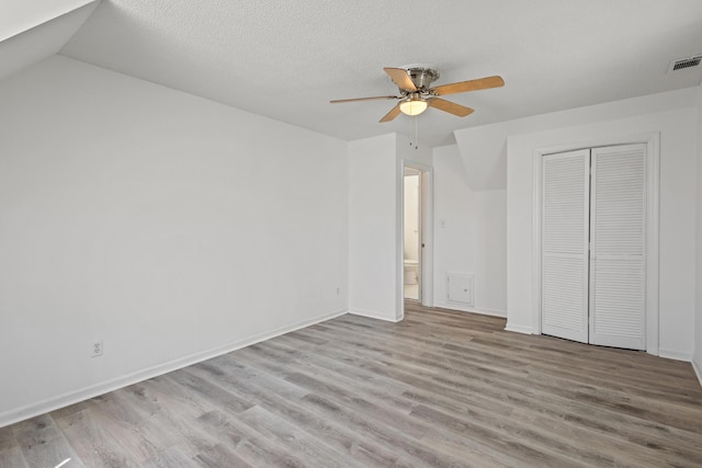 unfurnished bedroom featuring a closet, visible vents, light wood-style floors, a textured ceiling, and baseboards