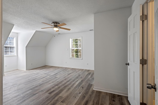 bonus room featuring a textured ceiling, wood finished floors, visible vents, a ceiling fan, and baseboards