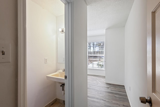 bathroom with baseboards, a textured ceiling, and wood finished floors