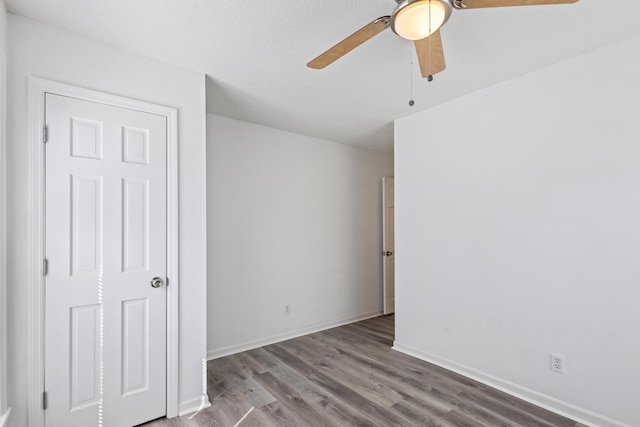 unfurnished bedroom with wood finished floors, a ceiling fan, and baseboards