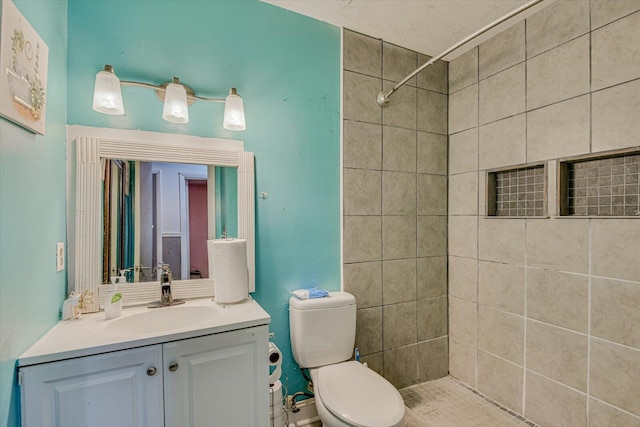 bathroom featuring vanity, a tile shower, a textured ceiling, and toilet