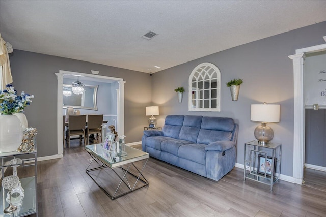 living room with hardwood / wood-style flooring, ceiling fan, a textured ceiling, and decorative columns