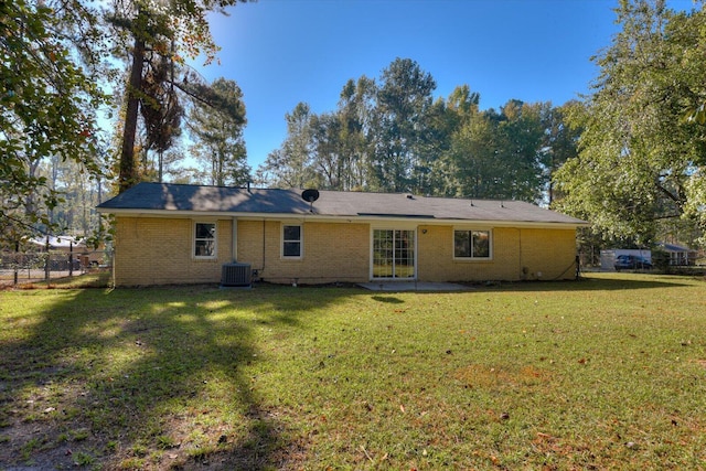 rear view of house featuring central air condition unit and a yard