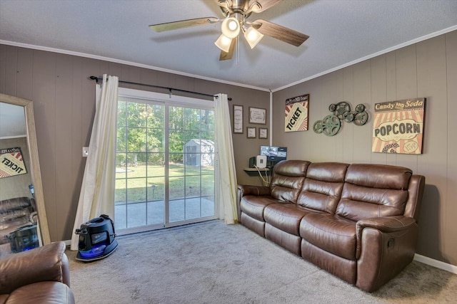 carpeted living room featuring ceiling fan, wood walls, a textured ceiling, and ornamental molding