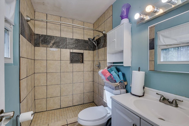 bathroom with tiled shower, vanity, and toilet