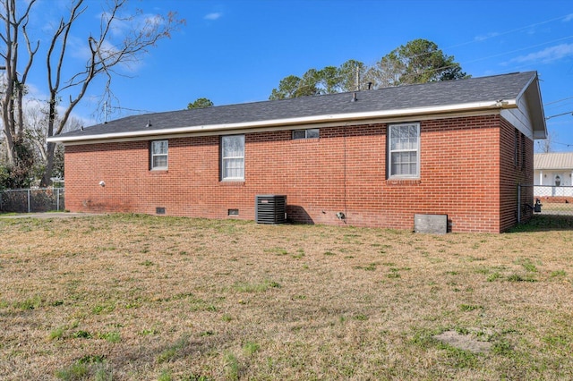 rear view of property with a lawn and central air condition unit