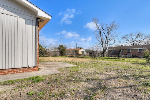 view of yard with a trampoline and a patio area