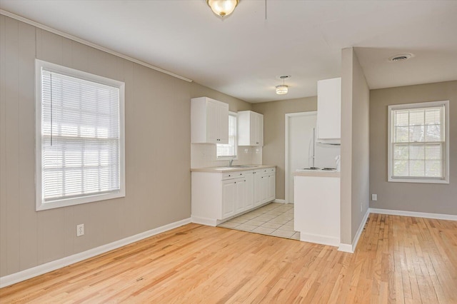 kitchen featuring white cabinetry, backsplash, sink, and light wood-type flooring