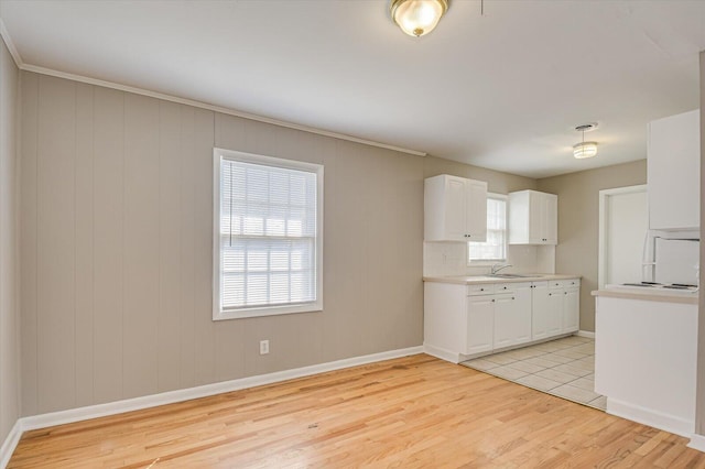 kitchen with backsplash, sink, light wood-type flooring, and white cabinets