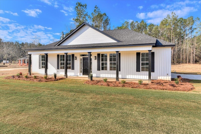 view of front of home with a shingled roof, covered porch, board and batten siding, and a front lawn