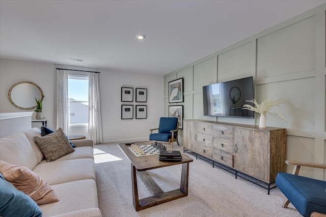 living room with baseboards, visible vents, a decorative wall, and light colored carpet