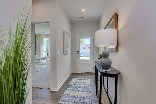 doorway to outside featuring plenty of natural light, visible vents, dark wood-type flooring, and baseboards