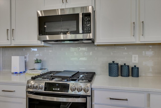 kitchen featuring appliances with stainless steel finishes, backsplash, white cabinetry, and light stone countertops