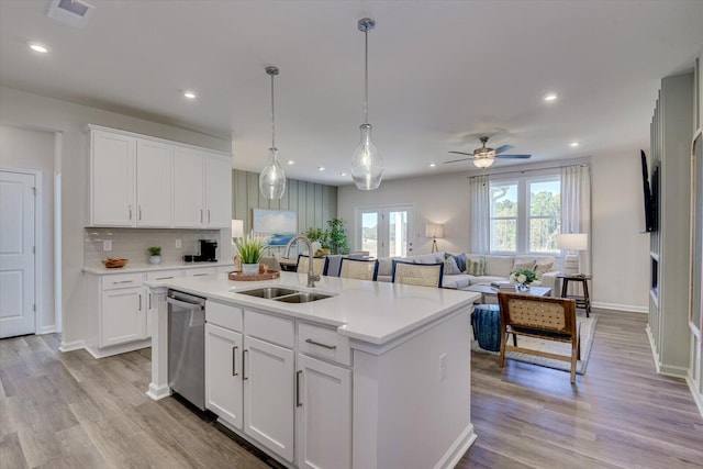 kitchen featuring a sink, visible vents, light countertops, dishwasher, and an island with sink