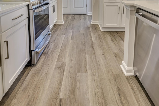 details featuring light wood-type flooring, appliances with stainless steel finishes, white cabinets, and light countertops